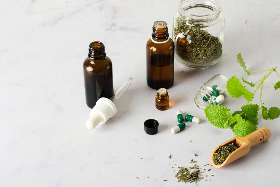 Herbal medicine bottles, capsules, and dried herbs on table
